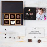 Open 6-chocolate box showing 1st birthday invitation card with photo